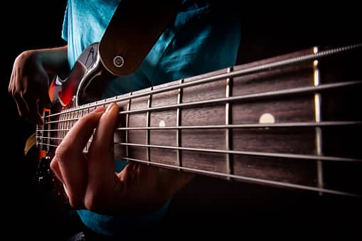 Young man playing a five string bass guitar